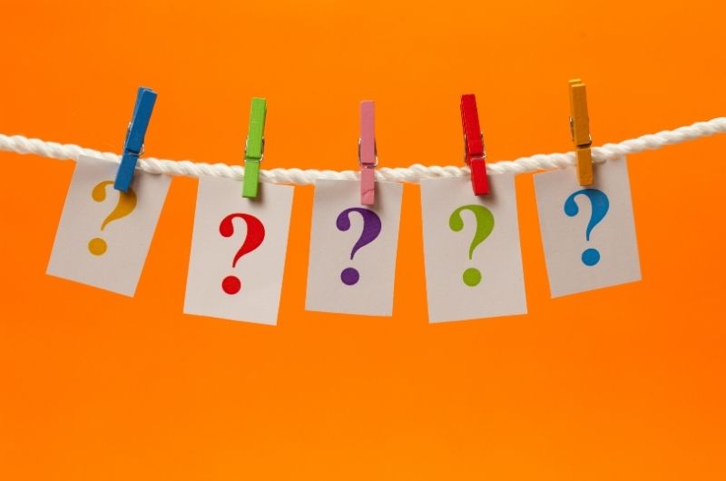 Five coloured clothes pegs holding five cards with question marks on a rope